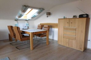 A room with a dining table, chairs, a wardrobe, and a skylight. - Panorama with indoor swimming pool (Hauzenberg)