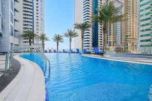 A swimming pool with blue water, surrounded by palm trees and modern buildings. - Stayshort - Stylish 2-bedroom Escape in Dubai Marina for 4 Guests (Dubai)