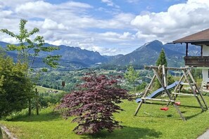 Eine Rasenfläche mit einem Spielplatz und einem Gebäude mit Schrägdach.