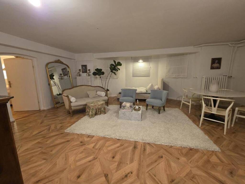 Ein Wohnzimmer mit einer Couch, Sesseln, einem Couchtisch und einem Esstisch.