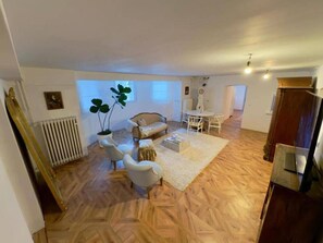 A spacious living area with a herringbone floor pattern, a sofa, a coffee table, and a dining table with chairs. - Stylish living in a 95-square-meter apartment with a great view from the garden (Bad Laasphe)