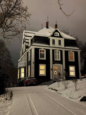 A large, dark-colored house with multiple windows and a snow-covered driveway. - Stylish living in a 95-square-meter apartment with a great view from the garden (Bad Laasphe)