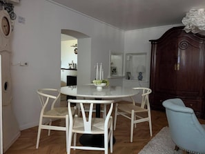 Et spiseområde med et rundt bord, fire stole, et træskab og en blå lænestol.