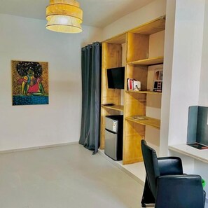A modern room with a flat-screen TV, a bookshelf, a desk, and a chair.