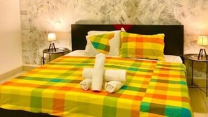 Una cama con colcha a cuadros, almohadas y toallas enrolladas.