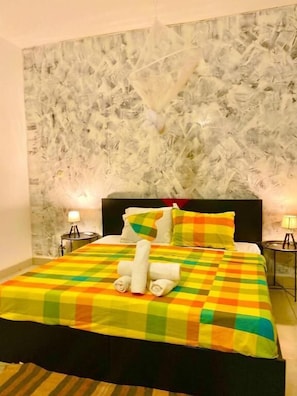 Un lit avec une couvre-lit à carreaux, des oreillers et des serviettes enroulées.