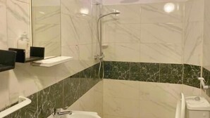 Un baño con ducha, inodoro, lavabo y espejo.