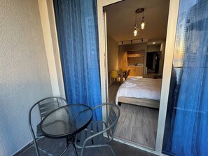 A hotel room with a bed, a table, and chairs, and a view of the outside. - Cozy 1-bedroom studio in peaceful Batumi with AC (Batumi)