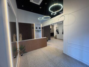 A modern reception area with a reception desk, wall-mounted clocks, and a sign that reads 'KOMENNA 10WIER'. - Cozy 1-bedroom studio in peaceful Batumi with AC (Batumi)