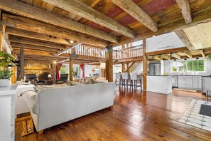 Un'ampia zona giorno con soffitto in legno, un divano, angolo cottura con bancone e parete in pietra.