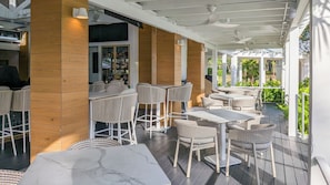Un espacio de patio al aire libre con mobiliario de mimbre, una barra con botellas y vistas a zonas verdes.