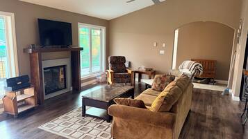 A living room with a fireplace, sofa, coffee table, and a television.