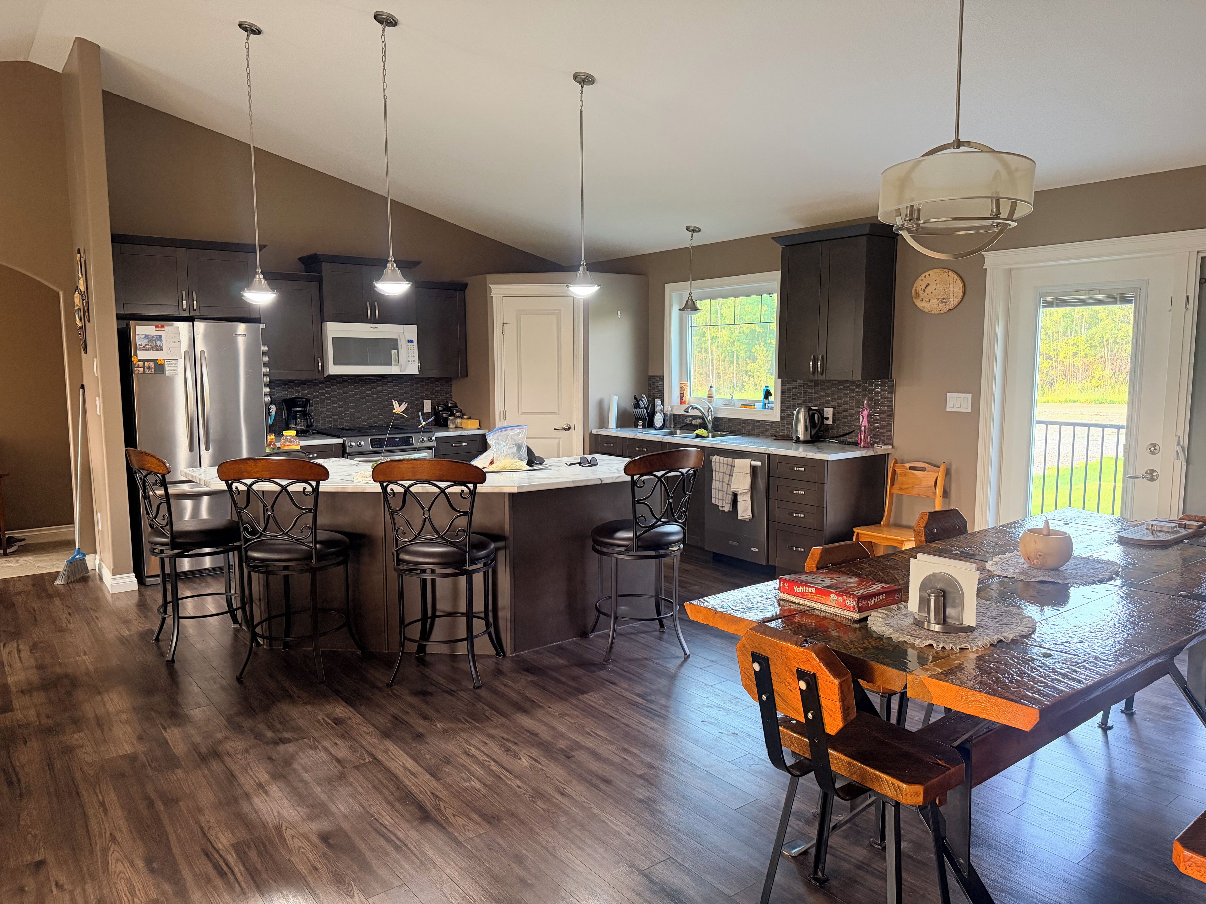 A modern kitchen with a central island, bar stools, and pendant lighting.