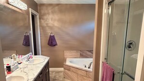 Un bagno con un doppio lavabo, una vasca da bagno e un box doccia in vetro.