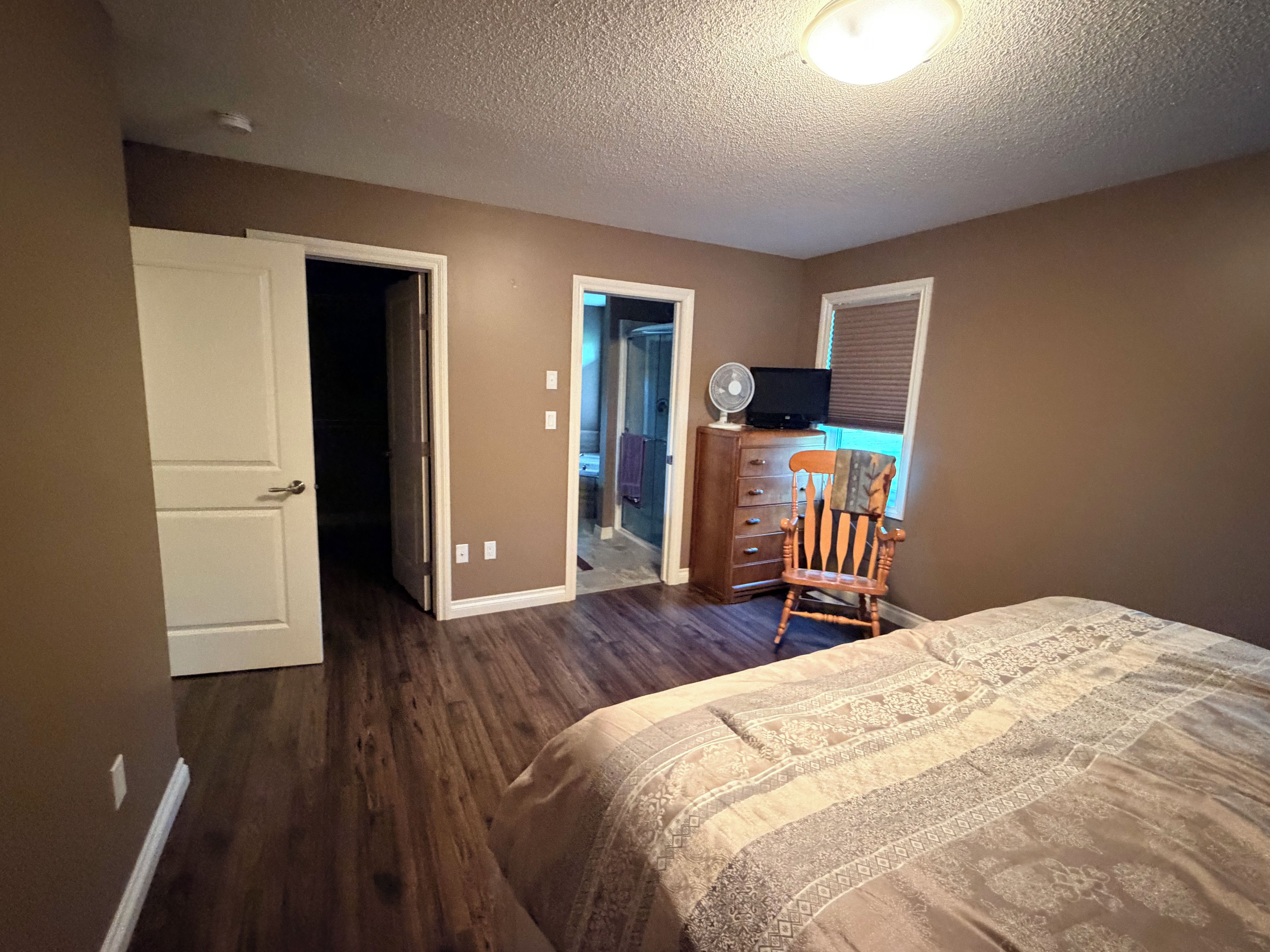 A bedroom with a bed, a dresser, a chair, and a television.