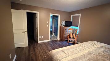 A bedroom with a bed, a dresser, a chair, and a television.