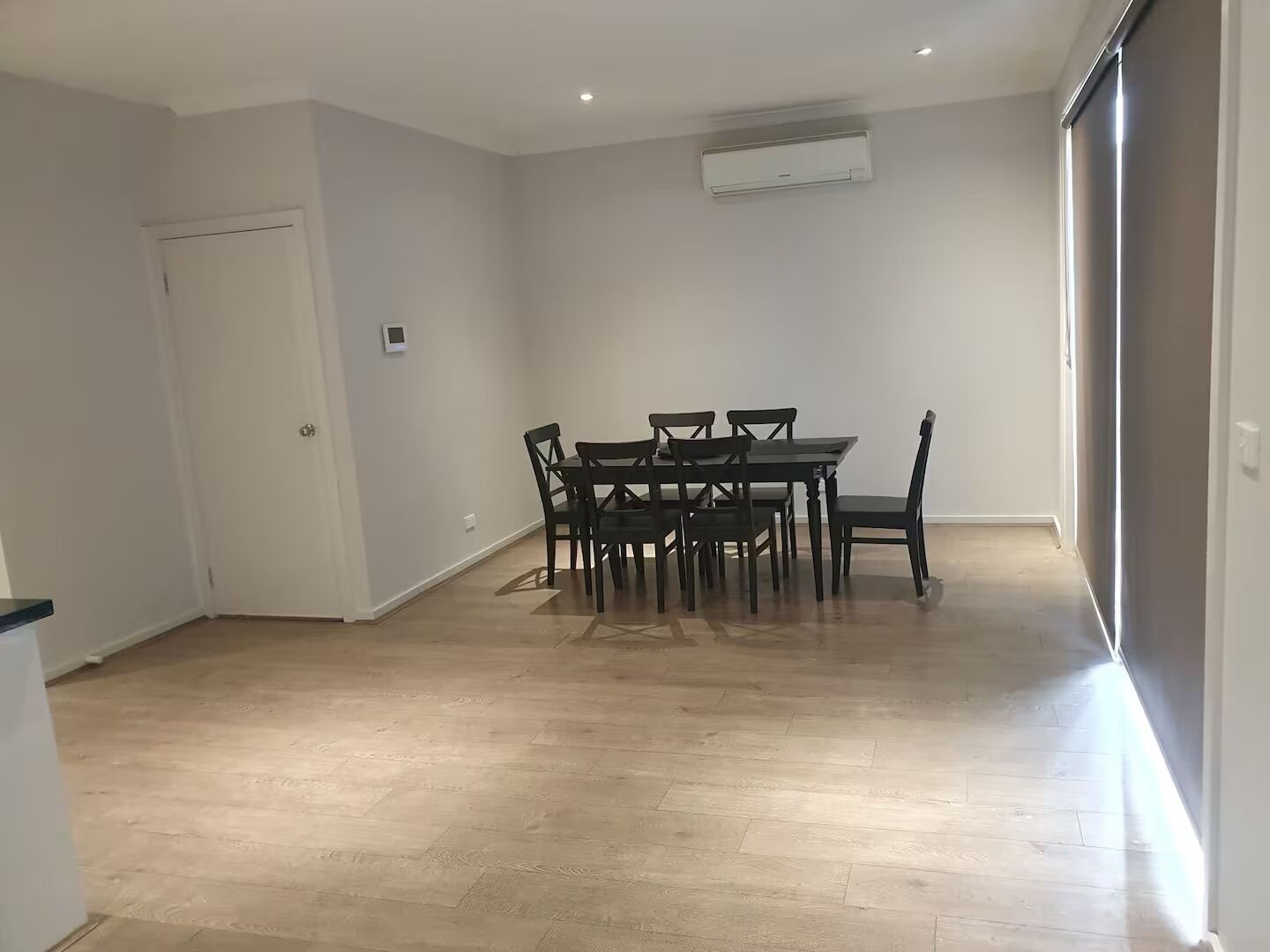 Un comedor con una mesa, sillas, una puerta y un equipo de aire acondicionado instalado en el techo.