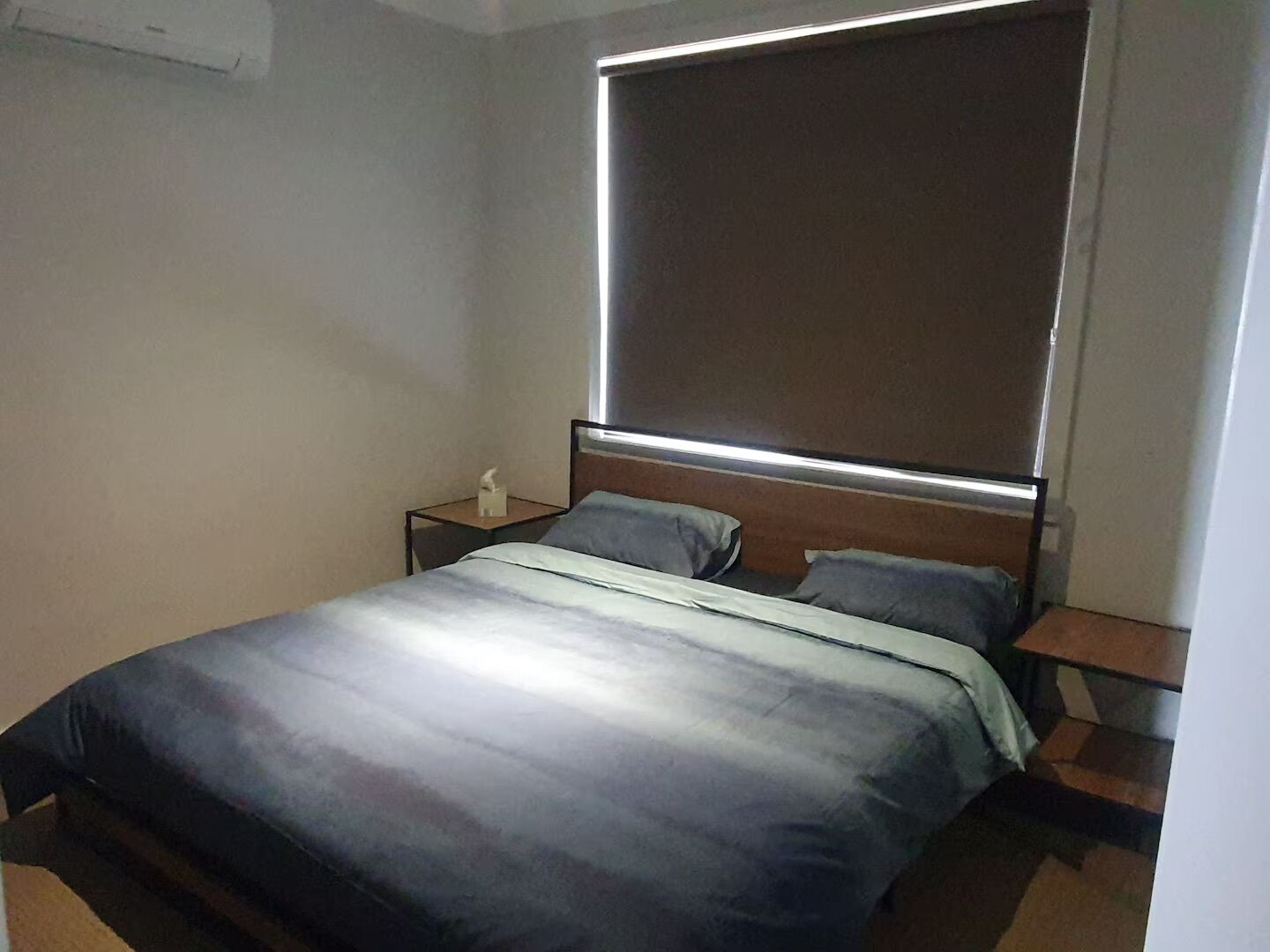 Un dormitorio con cama, mesitas de noche y una lámpara fijada a la pared.