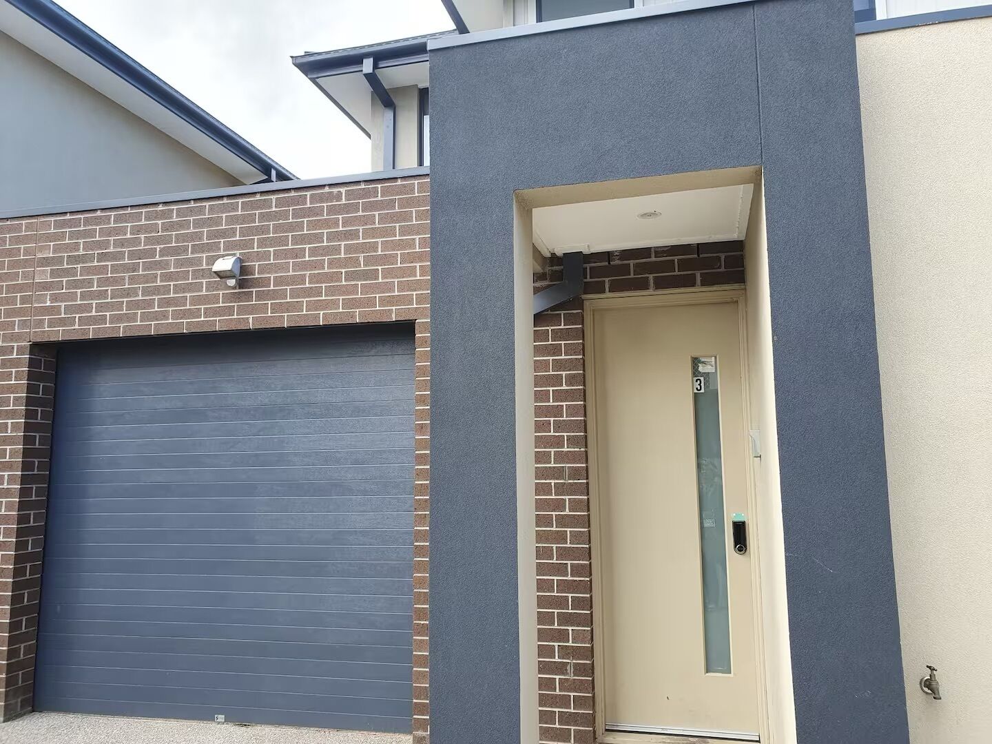 Un edificio con una puerta de garaje cerrada, un número de puerta y una ventana pequeña.