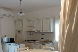 A compact kitchen with white cabinets, a microwave, and a gas stove. - Holiday apartment with 1 bedroom (Orosei)