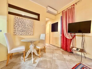 A room with a round table, two chairs, a flat-screen TV, and a patterned wall decoration. - Charming Holiday Suites in the Heart of Cannero Riviera, Lake Maggiore (Cannero Riviera)