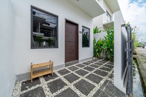 A modern building with a white exterior, a wooden bench, and a paved entrance area. - Senja Villa – Peaceful modern villa in tropical Bali (Kediri)