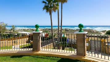 A balcony with a view of the ocean, palm trees, and a clear sky.