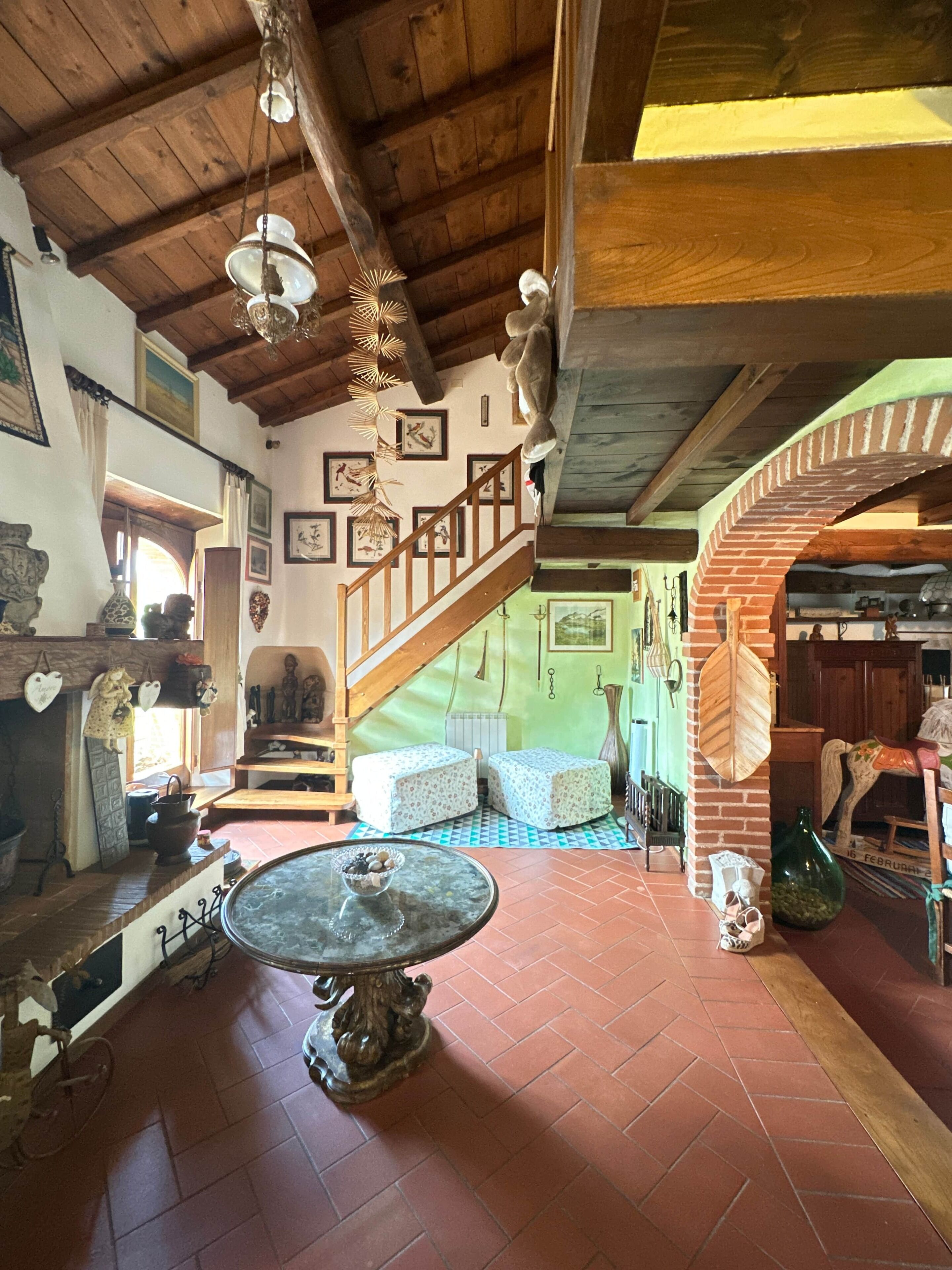 Ein rustikales Interieur mit einer Holztreppe, einem runden Tisch mit einer Schüssel und einer Ziegelwand.
