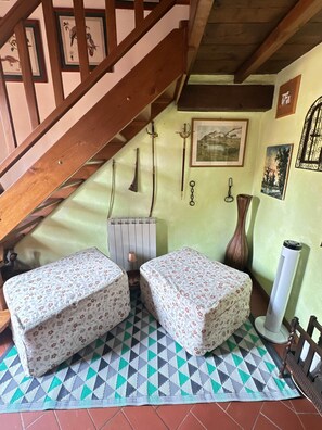 A room with a wooden staircase, two beds with floral bedding, a radiator, a vase, and wall-mounted pictures. - A Unique Tuscan Hideaway in Camaiore (Camaiore)