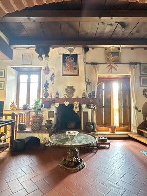 Una habitación tradicional con chimenea, una mesa redonda y varios objetos decorativos.