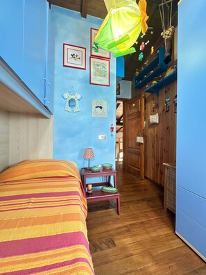 A room with a bed, a small table with a lamp, and a wall decorated with framed pictures. - A Unique Tuscan Hideaway in Camaiore (Camaiore)