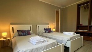 Een hotelkamer met twee eenpersoonsbedden, een nachtkastje met een lamp en een houten vloer.