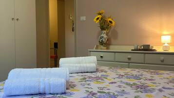 A hotel room with a bed, a nightstand, a lamp, and a vase with flowers.