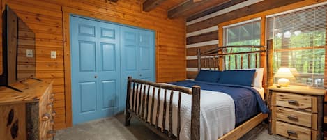 Une chambre dans une cabane en bois, avec un lit, une commode et une porte bleue.