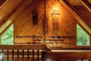 A wooden interior with a sloped ceiling, wooden beams, and a window with a view of trees. - Cozy 2-bedroom cabin in tranquil Sylva with AC (Sylva)