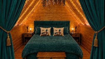 A cozy bedroom with a wooden ceiling, a teal bedspread, and matching pillows.