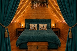 A cozy bedroom with a wooden ceiling, a teal bedspread, and matching pillows.