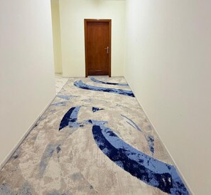 A hallway with a patterned carpet and a wooden door at the end. - TIDY Premium Stay Dubai (Dubai)