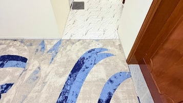 A hallway with a patterned floor leading to a door.