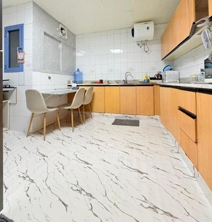 A kitchen with a marble floor, wooden cabinets, a sink, and a dining area with chairs. - TIDY Premium Hostel Dubai (Dubai)