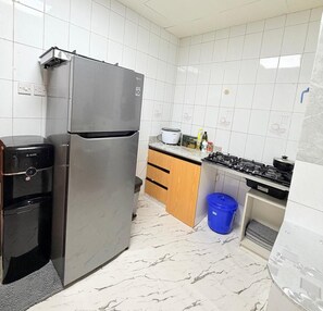 A compact kitchen with a stainless steel refrigerator, a built-in oven, and a gas stove. - TIDY Premium Stay Dubai (Dubai)