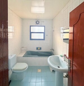 A bathroom with a toilet, sink, bathtub, and a window. - TIDY Premium Hostel Dubai (Dubai)