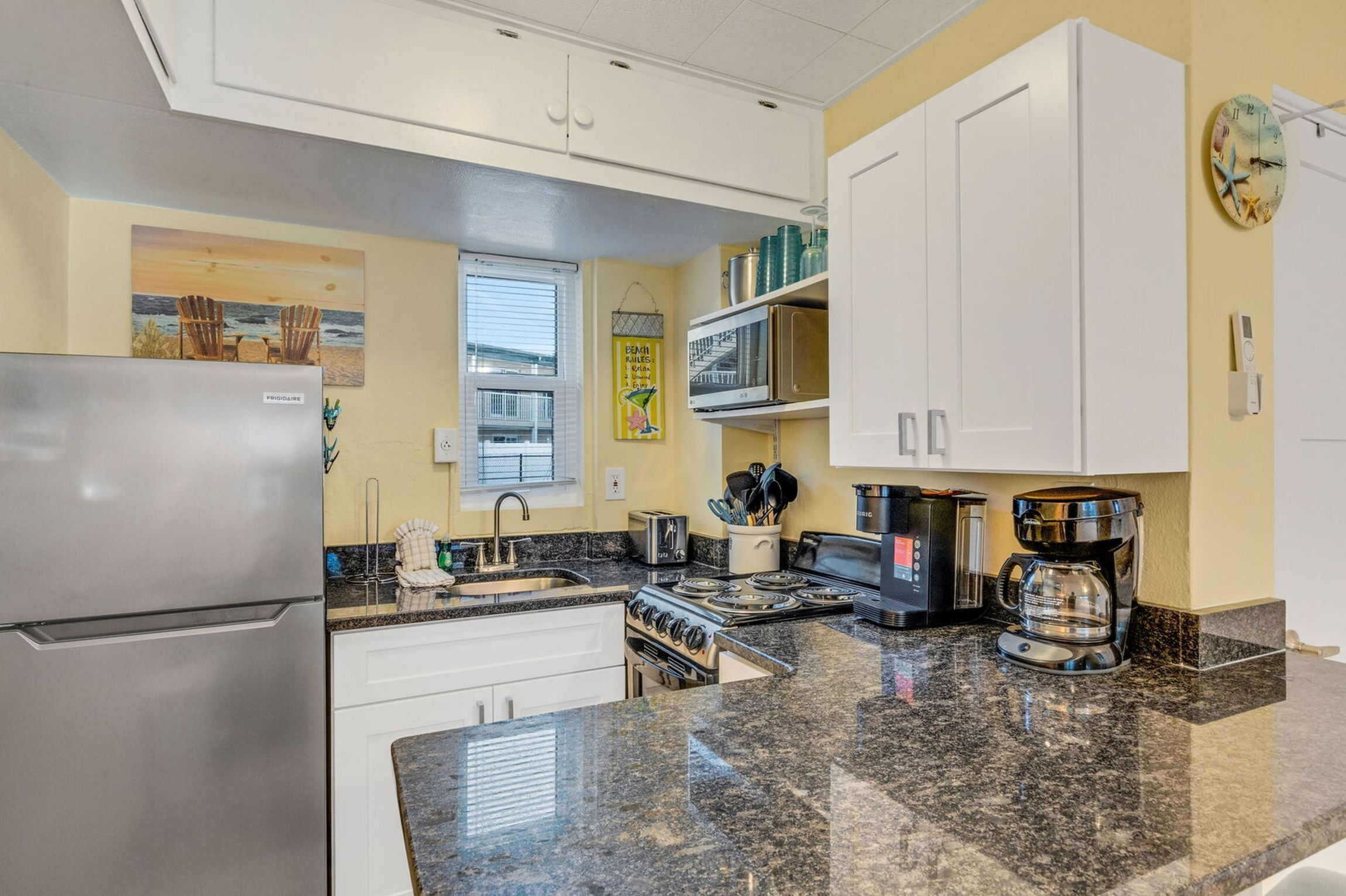 Una cocina compacta con refrigerador, estufa y cafetera.