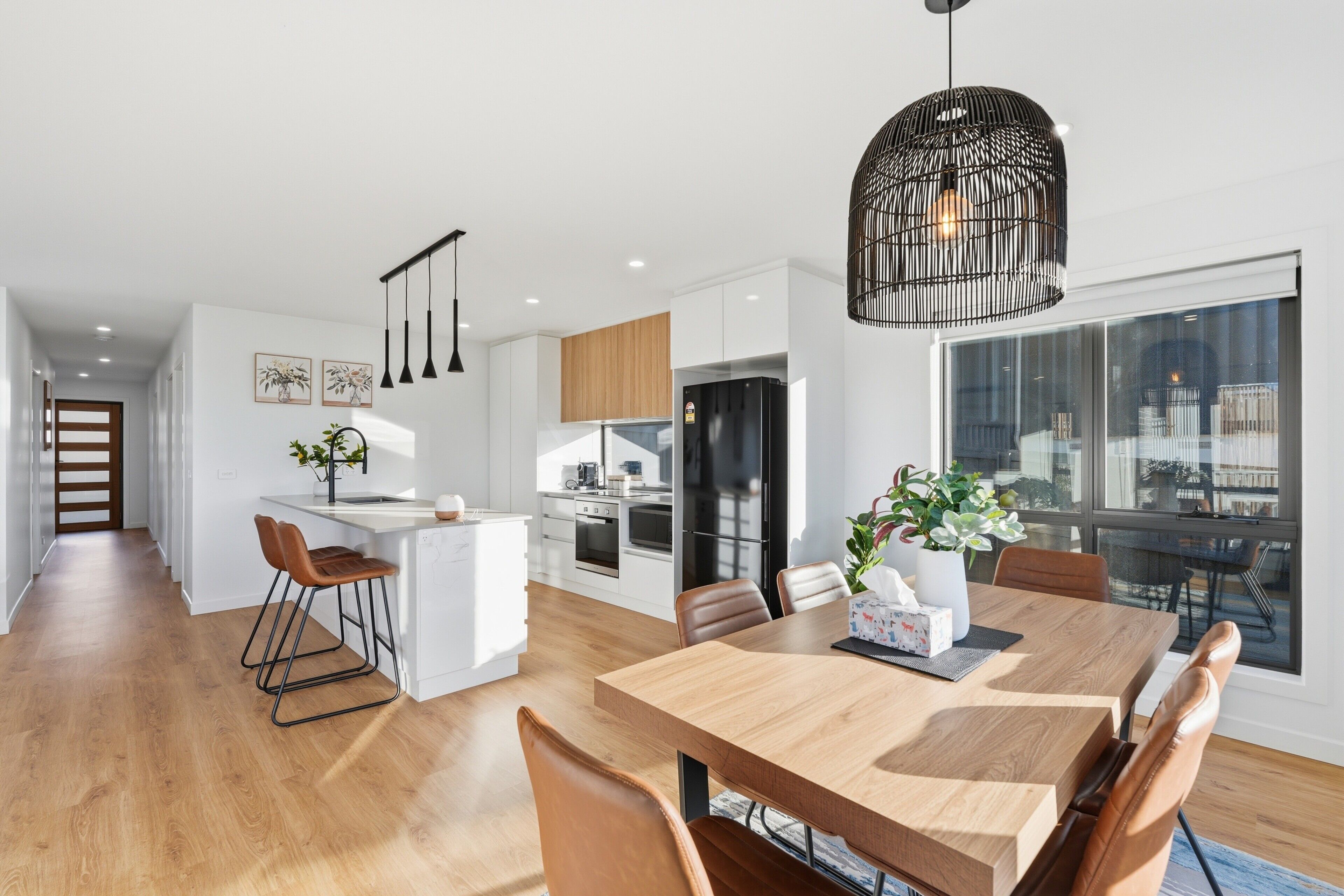 Une cuisine moderne avec des meubles blancs, un îlot central et des luminaires suspendus.