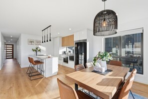 A modern kitchen with white cabinetry, a central island, and pendant lighting. - Waterside 3B Oasis | Private Parking & Scenic View (Midway Point)