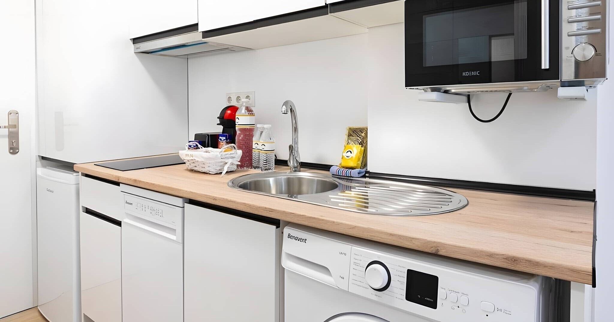 Une cuisine moderne équipée d’un évier, d’un four à micro-ondes et d’un lave-vaisselle.