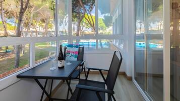Un balcon avec une table et des chaises, une bouteille de vin et deux verres.