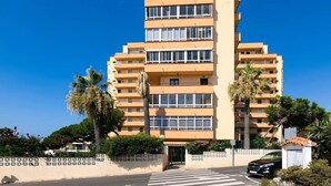 Un edificio residencial de varios pisos con balcones, una entrada con portón y un cielo despejado.