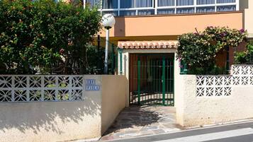 Une entrée d’immeuble avec une porte grillagée, une enseigne indiquant « EDF VIOLA » et un mur décoratif orné de motifs en treillis.
