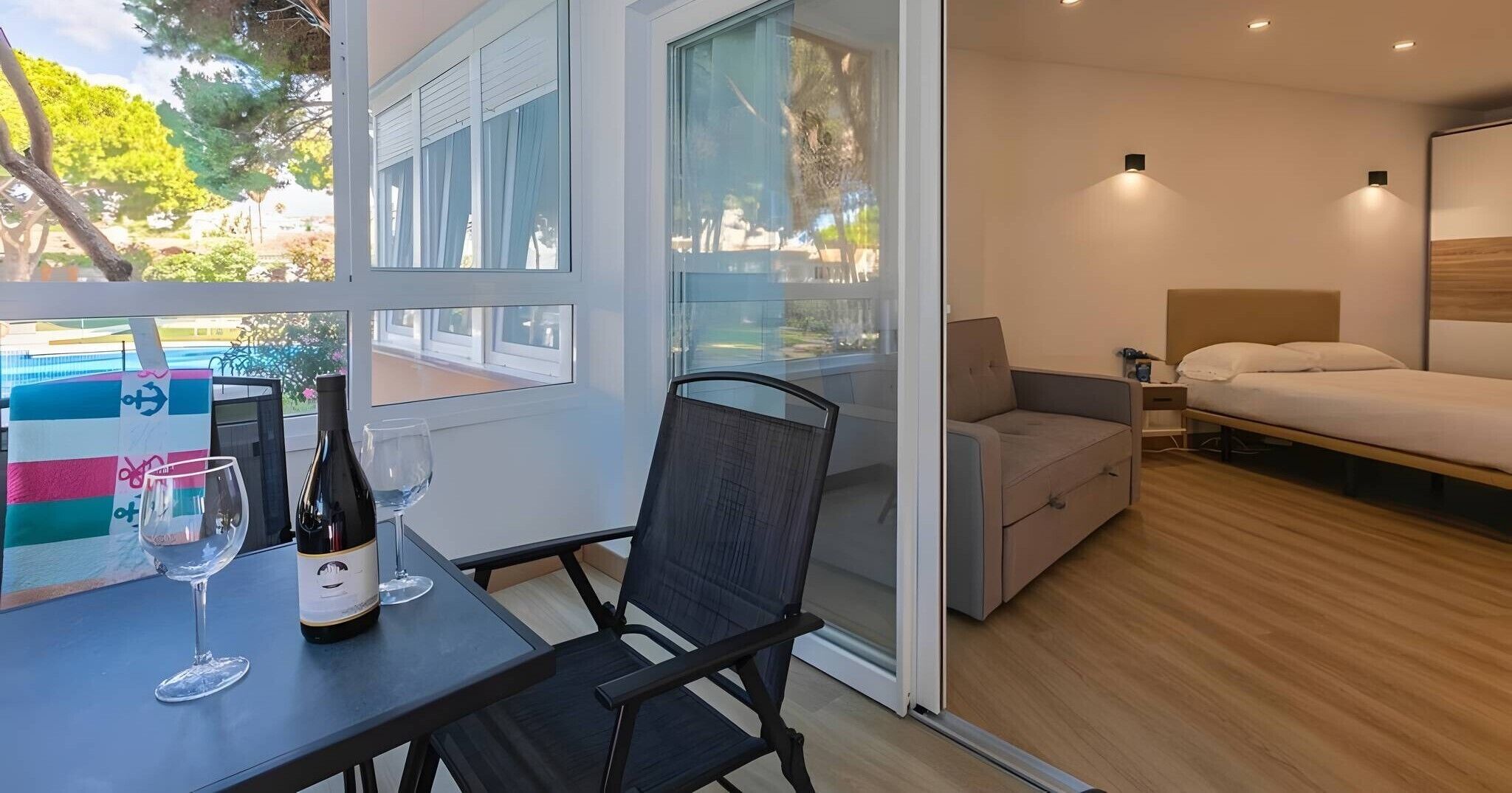 Une chambre à coucher moderne avec un lit, une petite table sur laquelle se trouvent une bouteille et un verre, et une chaise.